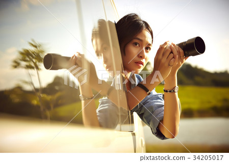 a young girl with digital camera is sitting in a truck and taking photos 34205017