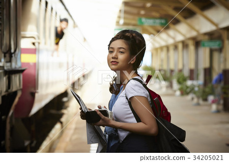 a young girl with backpack is standing near the train a young girl with backpack is standing near the train 34205021