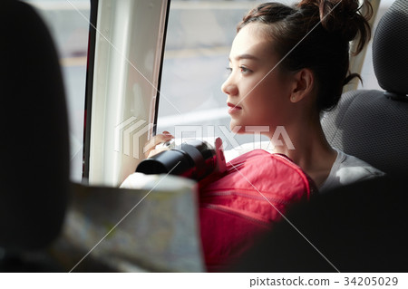 a young girl is holding a backpack and camera inside a truck 34205029