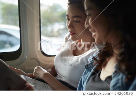 young female asian friends are looking the map inside a truck 34205030