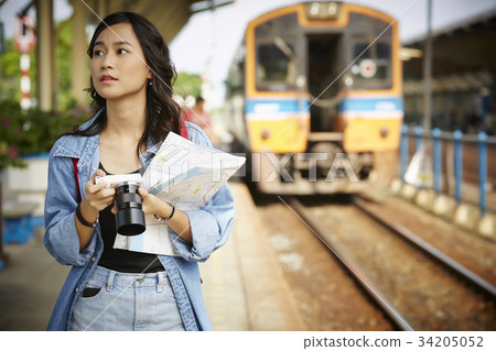 a female traveler is holding camera and walking near the train 34205052