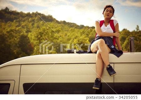 a young female traveler is sitting on truck's roof a young female traveler is sitting on truck's roof 34205055