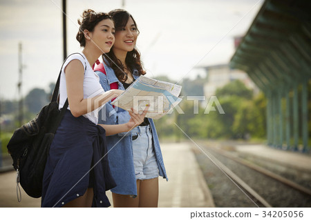 two young travelers are holding map and standing near a railway 34205056