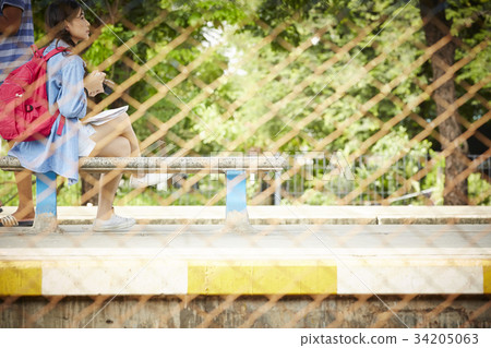 a young girl with camera and backpack is sitting on a rocky chair outdoors a young girl with camera and backpack is sitting on a rocky chair outdoors 34205063