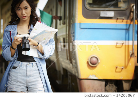 an asian girl is walking near the train and holding map and camera an asian girl is walking near the train and holding map and camera 34205067