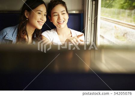 two girls are sitting in a train and watching outside 34205076