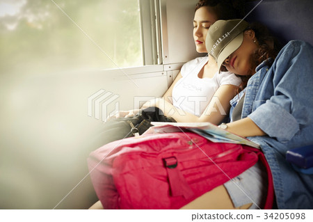 Two young Asian girls are sleeping on a train. 34205098