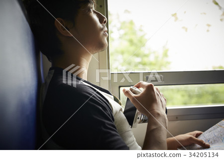 An Asian man is holding a camera and looking at something. An Asian man is holding a camera and looking at something. 34205134