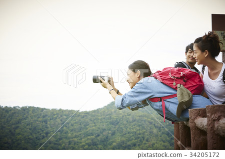 A young Asian girl is taking some photos of the sightseeing when travelling. 34205172