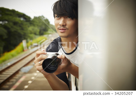 The man is looking outside of the train window to take the photo. 34205207