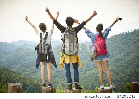 Three people are standing on the top of the moutain and enjoying the fresh air. Three people are standing on the top of the moutain and enjoying the fresh air. 34205212