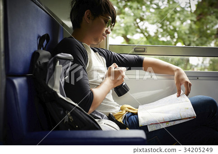 The man is reviewing a map when sititng on a train The man is reviewing a map when sititng on a train 34205249