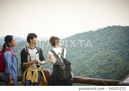 Three travellers are looking at the forest beyond the mountain 34205252