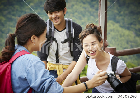 The girl is showing a funny photo in a camera to her boyfriend and girlfriend 34205266