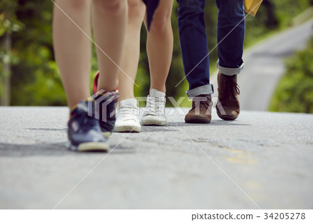 legs and feet of three people walking on a road legs and feet of three people walking on a road 34205278