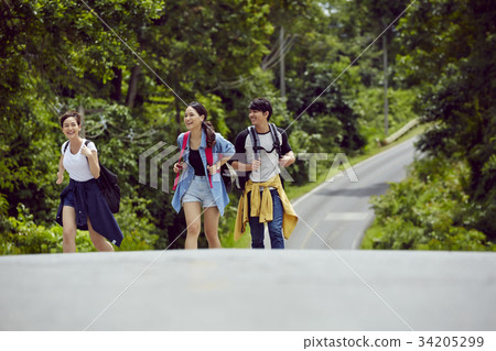three young asian travellers are walking on the street in the jungle three young asian travellers are walking on the street in the jungle 34205299