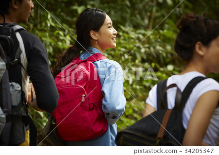 a pretty girl wearing a red backpack is smiling when walking in forest with friends a pretty girl wearing a red backpack is smiling when walking in forest with friends 34205347