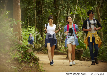 three asian persons are on the way to their destination in forest three asian persons are on the way to their destination in forest 34205361