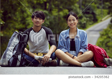 two asian young travellers with smile are sitting on the street two asian young travellers with smile are sitting on the street 34205362