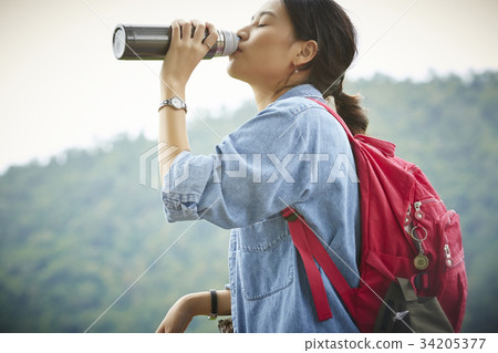 a beautiful asian woman is drinking water and relaxing 34205377