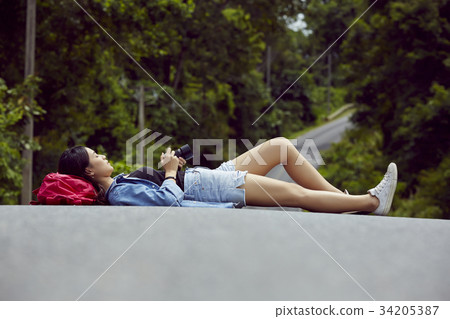 a pretty girl is lying on a road and looking at photos in her modern camera 34205387
