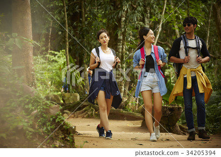 three young dynamic travellers are walking and talking together in forest 34205394