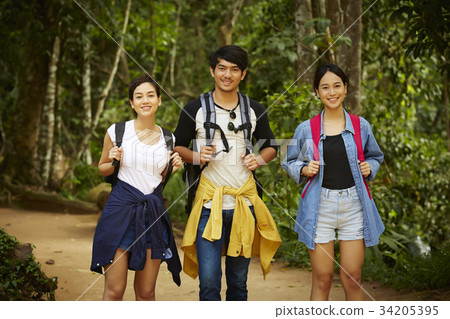 three young asian travellers are smiling and enjoying fresh air in forest 34205395