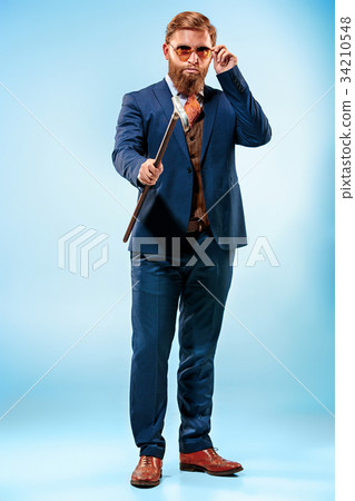 The barded man in a suit holding cane. 34210548