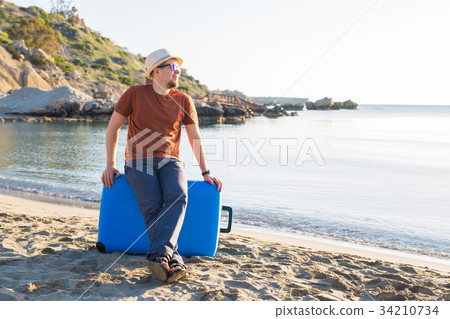 Man in sunglasses and hat with luggage on the sea 34210734