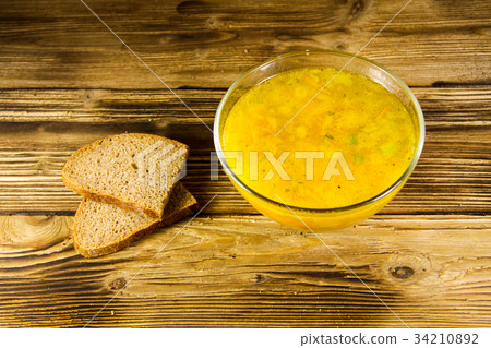 Fresh soup in glass bowl on wooden table 34210892