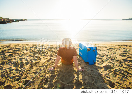 Man in sunglasses and hat with luggage on the sea 34211067