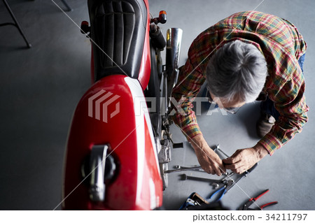 Senior man repairing a motorcycle 34211797
