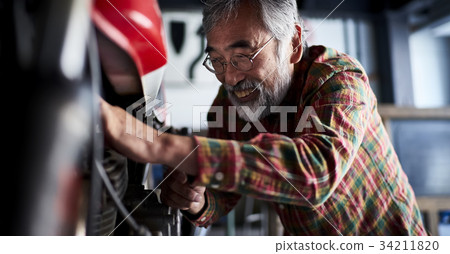 Senior man repairing a motorcycle Senior man repairing a motorcycle 34211820
