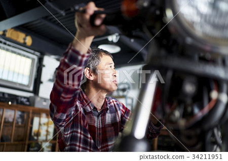 Senior man repairing a motorcycle Senior man repairing a motorcycle 34211951