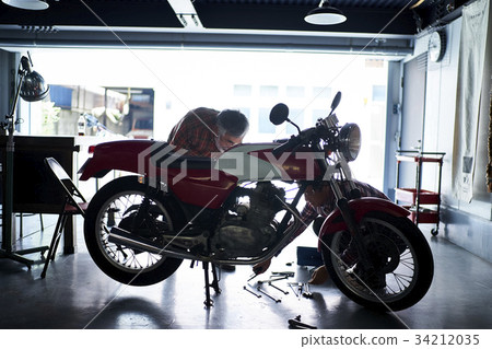 Senior man repairing a motorcycle 34212035