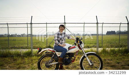 Woman straddling a bike Woman straddling a bike 34212299