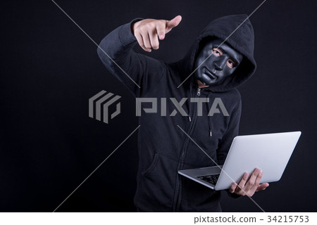 Male hacker with black mask carrying laptop 34215753