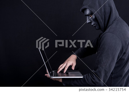 Male hacker with black mask carrying laptop 34215754