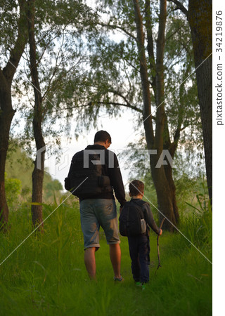 Father and son walking into the forrest at sunset Father and son walking into the forrest at sunset 34219876