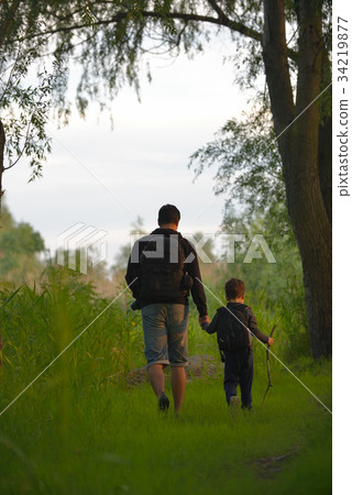 Father and son walking into the forrest at sunset Father and son walking into the forrest at sunset 34219877