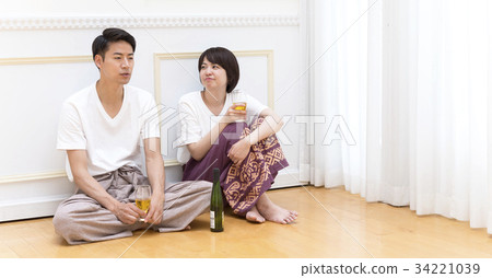 A couple sitting on the floor and tilting the glass 34221039