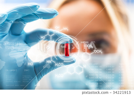 Young attractive female scientist holding red pill Young attractive female scientist holding red pill 34221913