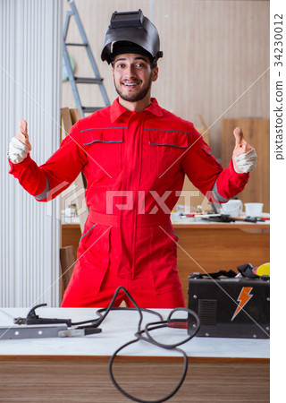 Young repairman with a welding gun electrode and a Young repairman with a welding gun electrode and a 34230012