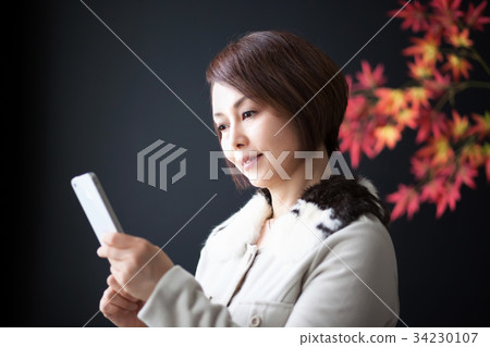 Middle woman smartphone operation autumn image Middle woman smartphone operation autumn image 34230107