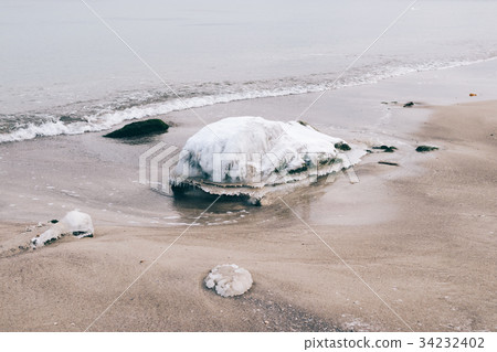 Icy stone is lying on the beach near the water Icy stone is lying on the beach near the water 34232402