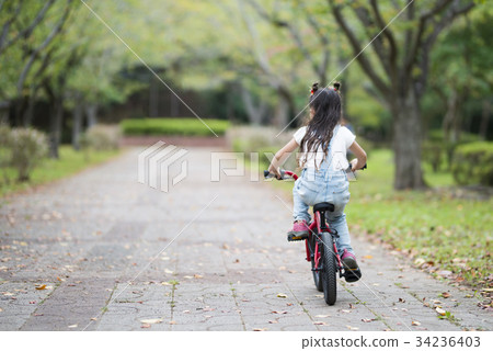 A girl riding a red bicycle 34236403