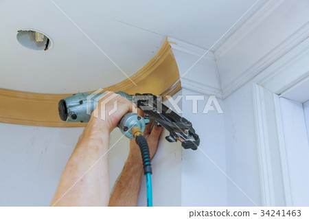 Carpenter brad using nail gun to Crown Moulding 34241463
