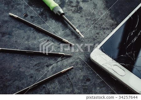 Smartphone with a broken screen and repair tools. 34257644