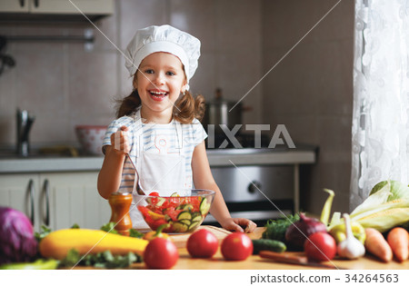 Healthy eating. Happy child girl prepares vegetable salad in ki Healthy eating. Happy child girl prepares vegetable salad in ki 34264563