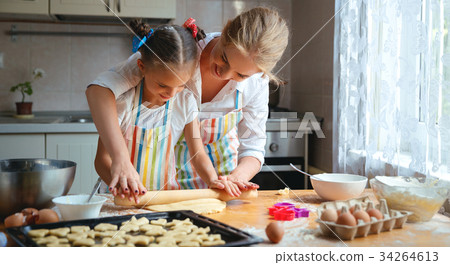 Happy family mother and daughter bake kneading dough in kitchen Happy family mother and daughter bake kneading dough in kitchen 34264613